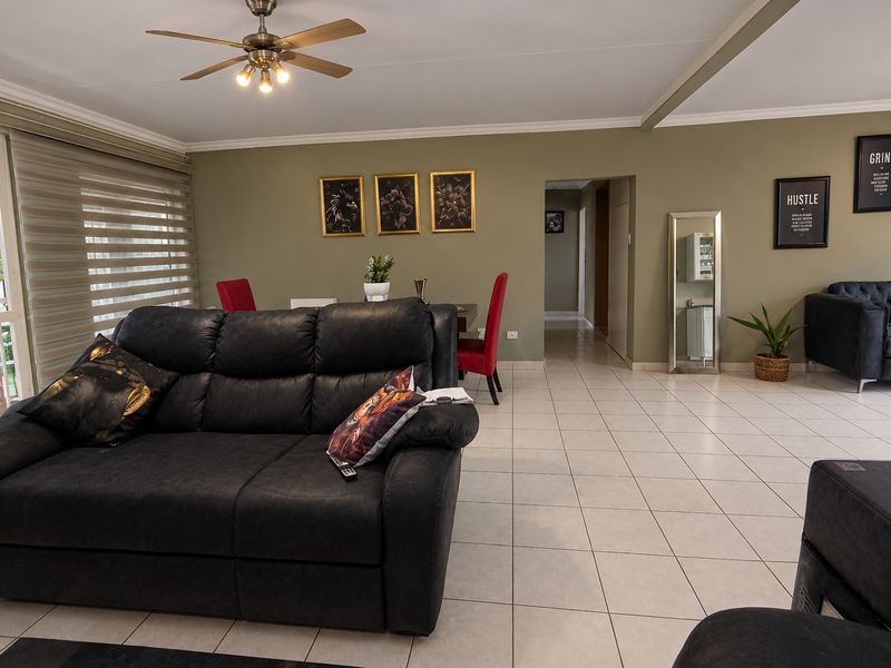 Spacious open-plan living and dining area featuring neutral tiled flooring, a ceiling fan, and large windows with modern roller blinds.
