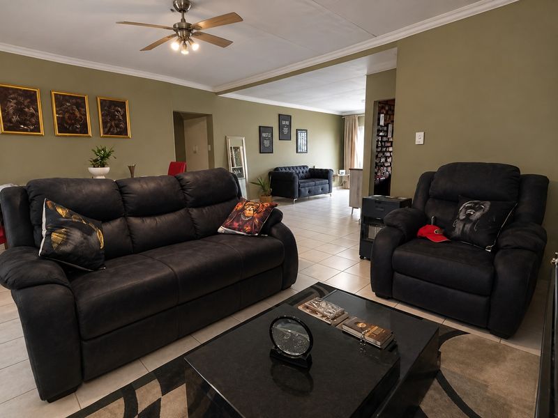 Spacious open-plan living area featuring neutral wall tones, tiled flooring, and a central ceiling fan, offering a versatile layout for comfortable family living.