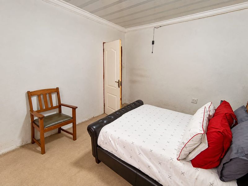 A bedroom featuring carpeted flooring, a panelled ceiling with coving, and a standard internal door. The room requires cosmetic updates to the walls and flooring.