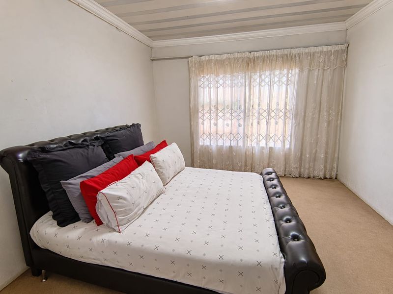 A bedroom featuring carpeted flooring, a security gate on the window, and decorative cornice detailing.