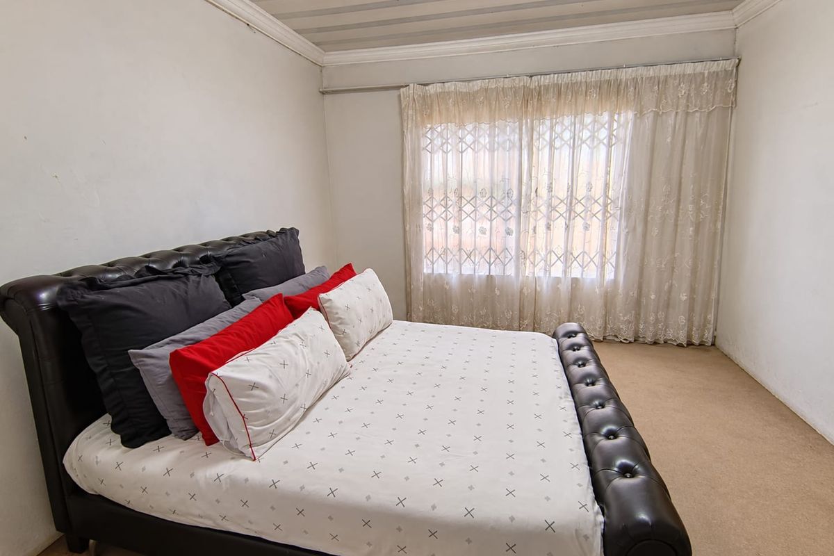 A bedroom featuring carpeted flooring, a security gate on the window, and decorative cornice detailing.