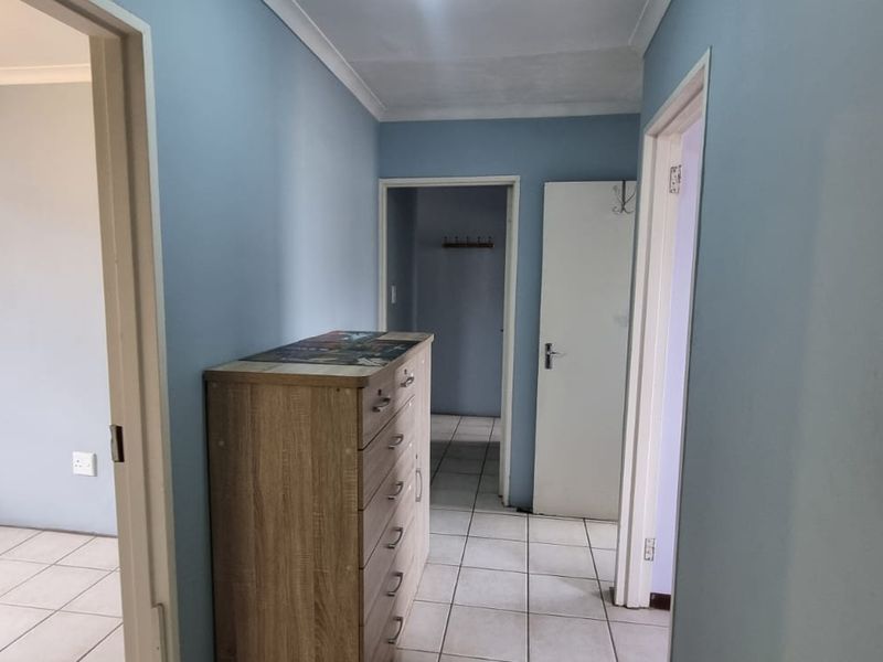 A functional hallway featuring tiled flooring and access to adjacent rooms, including a space equipped with a wall-mounted air conditioning unit.