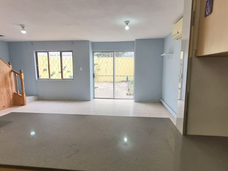 An open-plan living area featuring tiled floors, a stone breakfast counter, and direct access to the rear exterior through a sliding glass door.