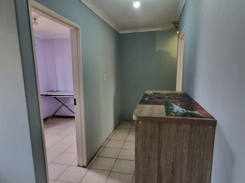 A functional hallway area with tiled flooring and neutral wall paint, providing access to adjacent rooms within the flat.