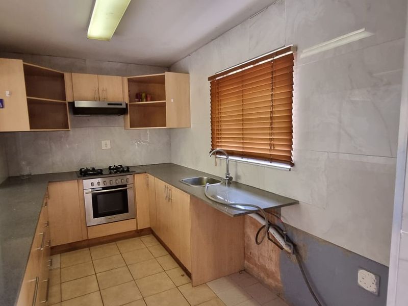 A functional kitchen featuring built-in cabinetry, a gas hob, and an electric oven, requiring minor repairs to the wall and plumbing area.