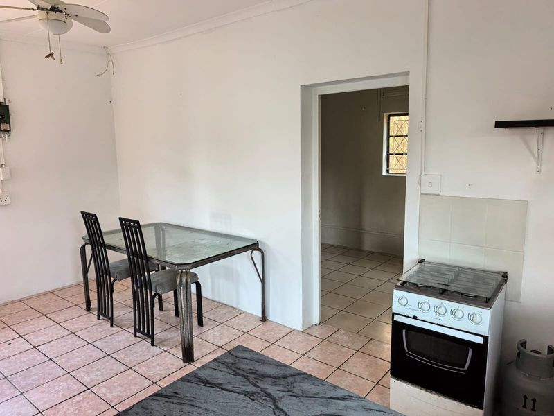 Open plan living and kitchen area featuring tiled flooring, a ceiling fan, and a gas stove, requiring cosmetic updates to improve the overall aesthetic.