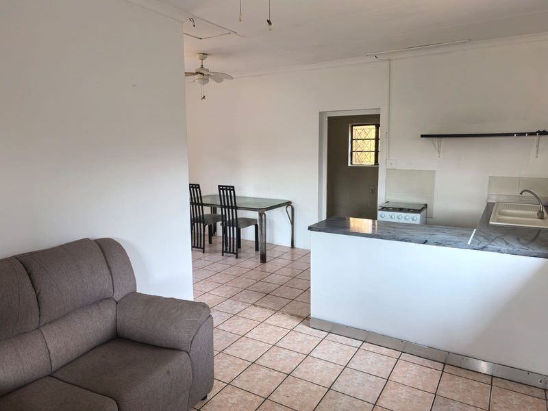 Open-plan living and kitchen area featuring tiled flooring, a breakfast counter, and a functional kitchen layout with a freestanding stove.