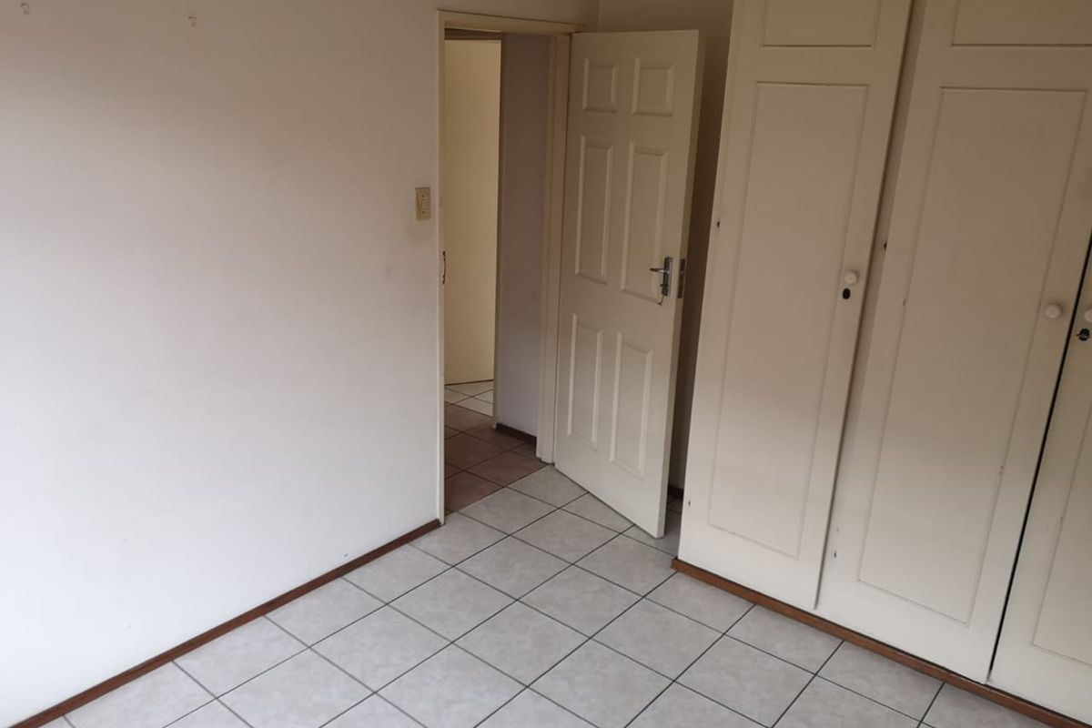 An empty bedroom featuring tiled flooring and built-in cupboards, offering a blank canvas for potential renovation or interior design updates.
