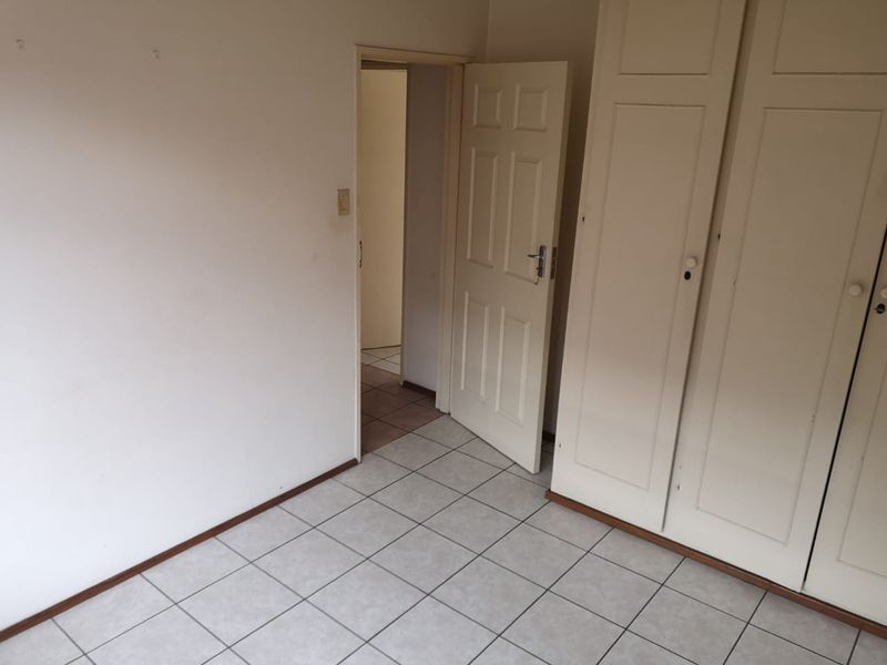An empty bedroom featuring tiled flooring and built-in cupboards, offering a blank canvas for potential renovation or interior design updates.