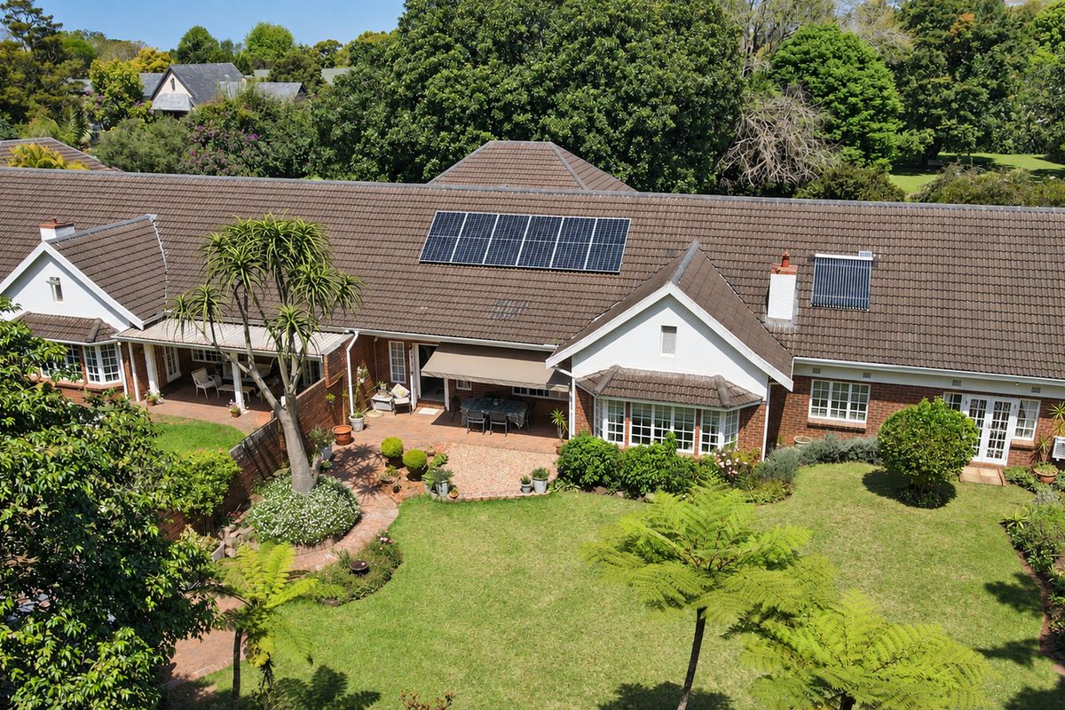 Aerial view of the townhouse rear elevation featuring a tiled roof with solar panels, brick facade, bay window, and a paved patio area.