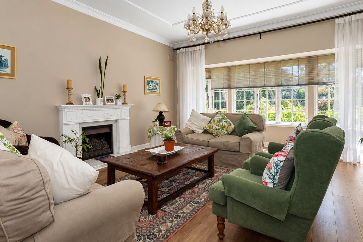 A comfortable living room featuring a classic fireplace with a mantelpiece, crown molding, and large windows that provide ample natural light.