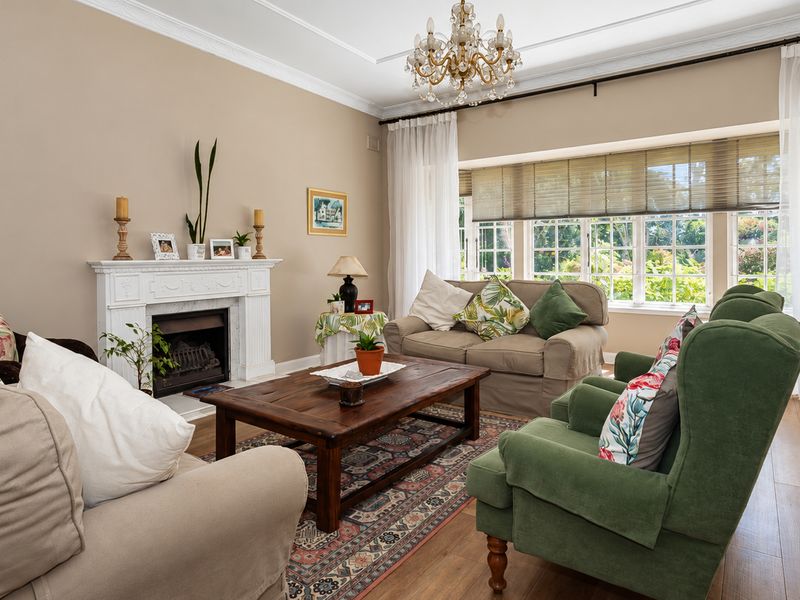 A comfortable living room featuring a classic fireplace with a mantelpiece, crown molding, and large windows that provide ample natural light.