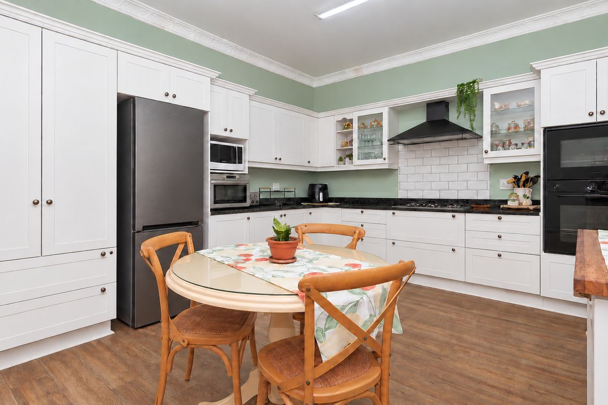 A well-appointed kitchen featuring white cabinetry, stone countertops, a subway tile backsplash, and integrated appliances including a gas hob and double oven.