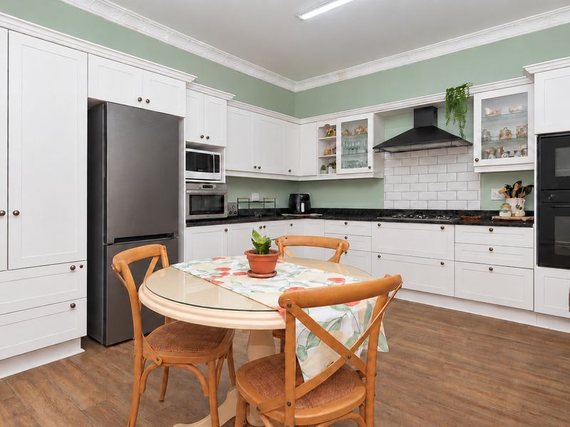 A well-appointed kitchen featuring white cabinetry, stone countertops, a subway tile backsplash, and integrated appliances including a gas hob and double oven.