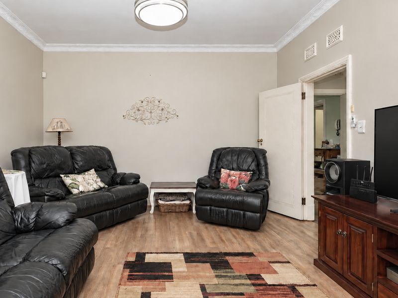 A comfortable living room featuring laminate flooring, decorative crown molding, and neutral wall tones, providing a functional and inviting space.