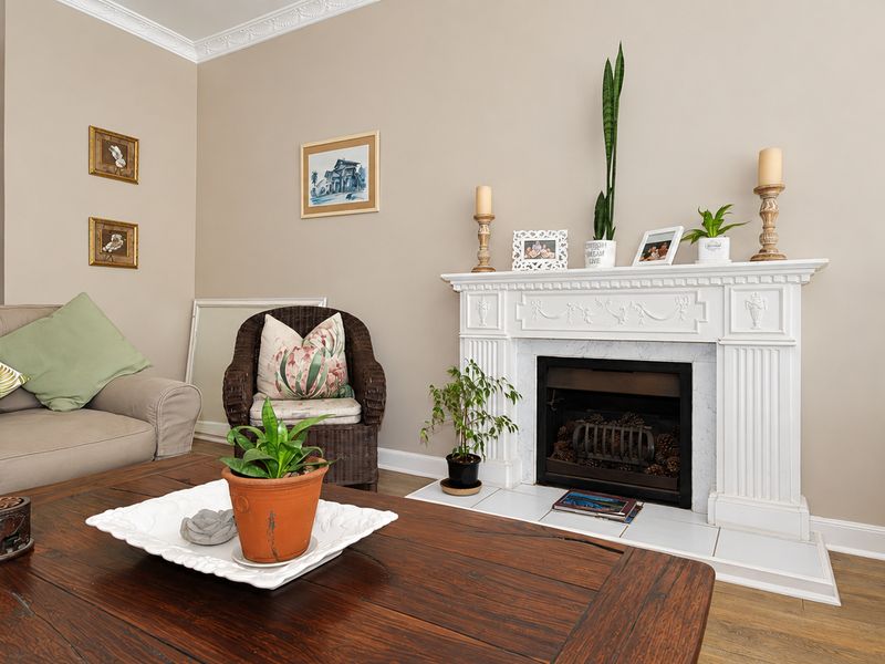 A cozy living room featuring a decorative fireplace with a white mantelpiece, built-in shelving, and crown molding, finished with laminate flooring.