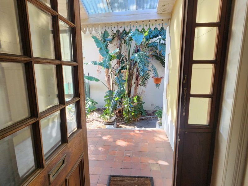 Entrance area featuring a classic timber framed glass door, decorative encaustic floor tiles, and a covered outdoor courtyard with terracotta flooring.