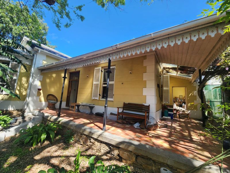 A covered veranda featuring terracotta tiling, decorative timber fretwork, and classic shutters, offering a charming outdoor space with potential for restoration.