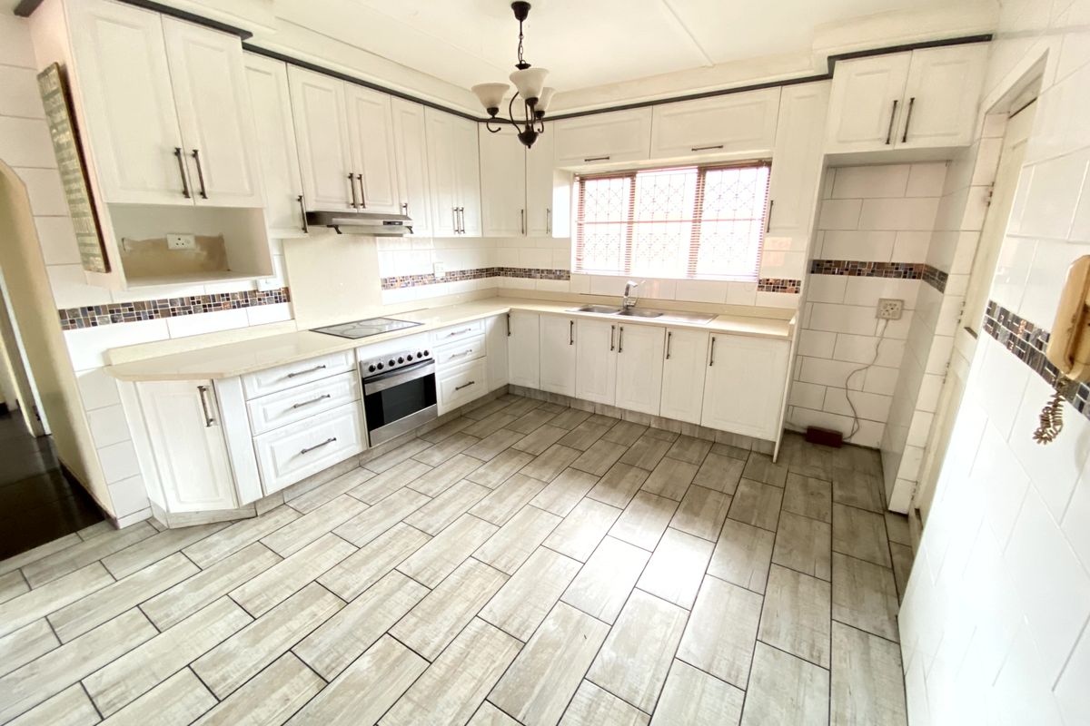 A functional kitchen featuring white cabinetry, tiled flooring, a built-in oven and hob, and a double sink with a tiled backsplash.