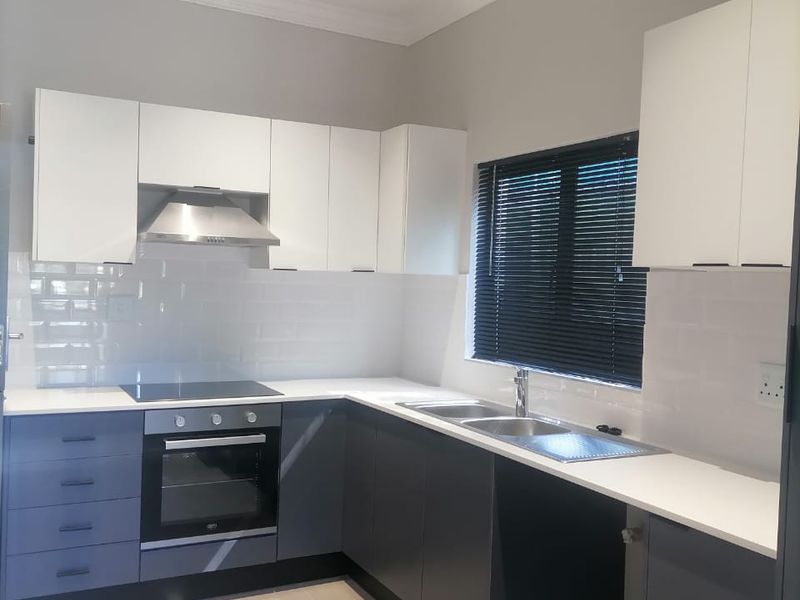 Modern kitchen featuring two-tone cabinetry, integrated oven and hob, tiled splashback, and a double sink with contemporary finishes.