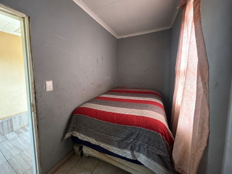 A compact bedroom featuring tiled flooring and coved ceilings, currently requiring cosmetic updates to the wall finishes.