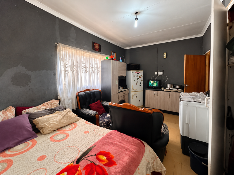 A bedroom featuring tiled flooring, built-in cabinetry, and coved ceilings. The walls show signs of wear and require maintenance or cosmetic updates.