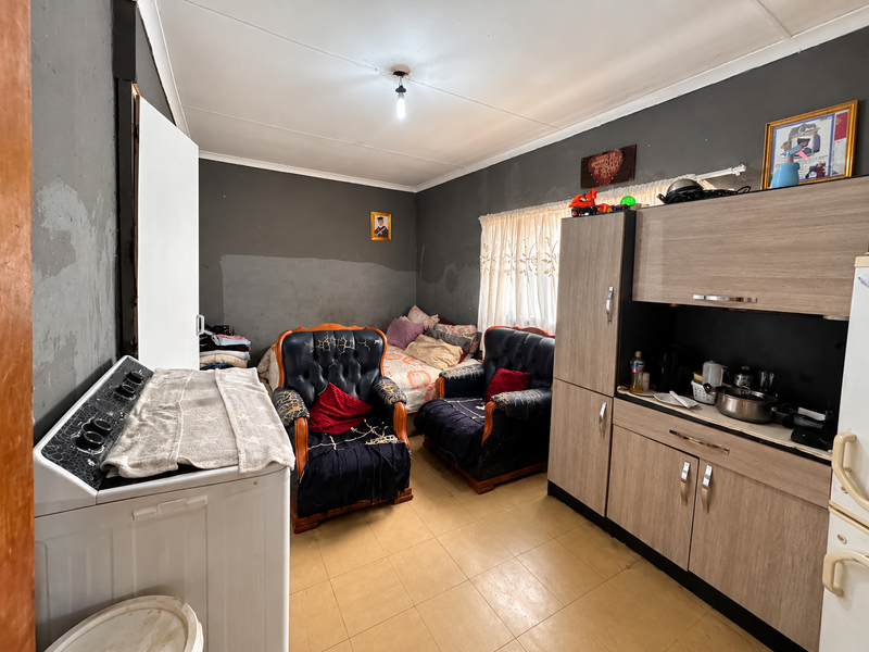 Open plan living area featuring built-in cabinetry and tiled flooring, currently used as a multi-purpose space with visible wall finish wear.