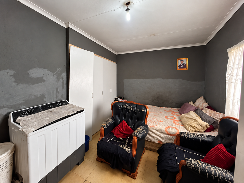 A bedroom featuring built-in wardrobes, tiled flooring, and coved ceilings. The walls require cosmetic attention and repainting to improve the overall aesthetic.