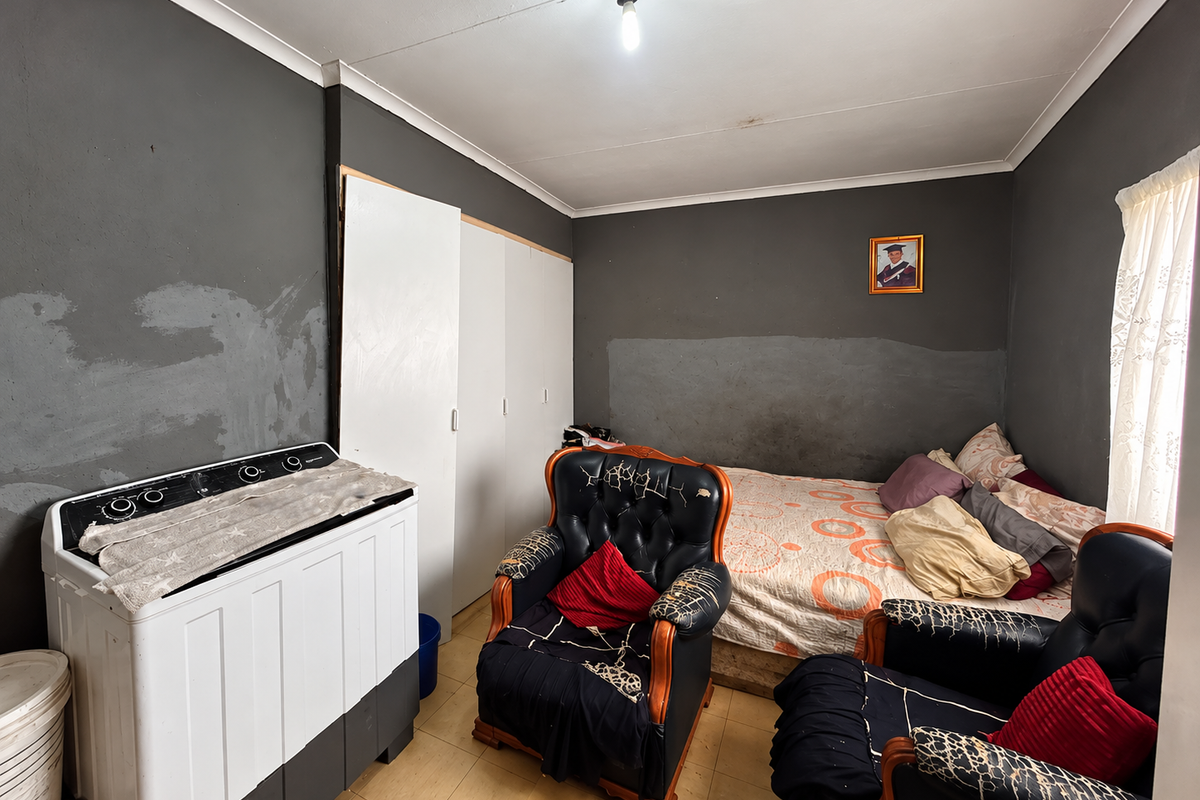 A bedroom featuring built-in wardrobes, tiled flooring, and coved ceilings. The walls require cosmetic attention and repainting to improve the overall aesthetic.
