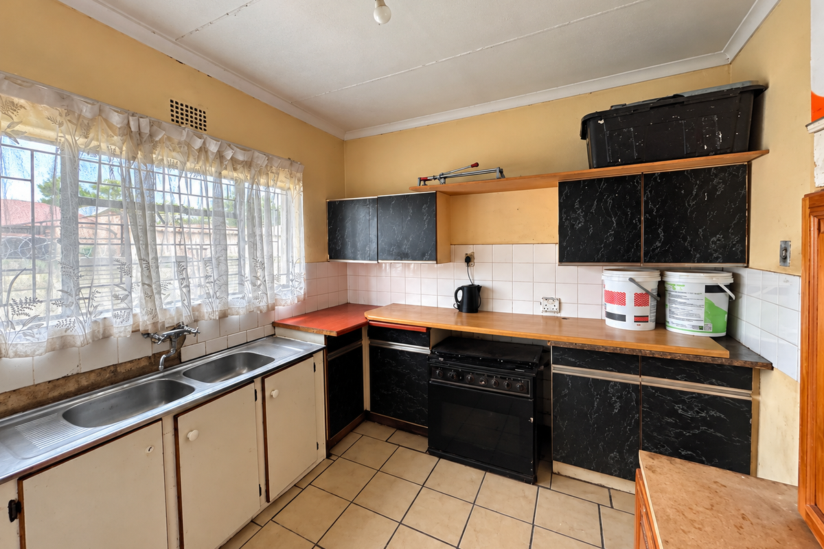 A functional kitchen featuring a double stainless steel sink, built-in oven, hob, and laminate countertops with ample storage cabinetry and tiled splashbacks.