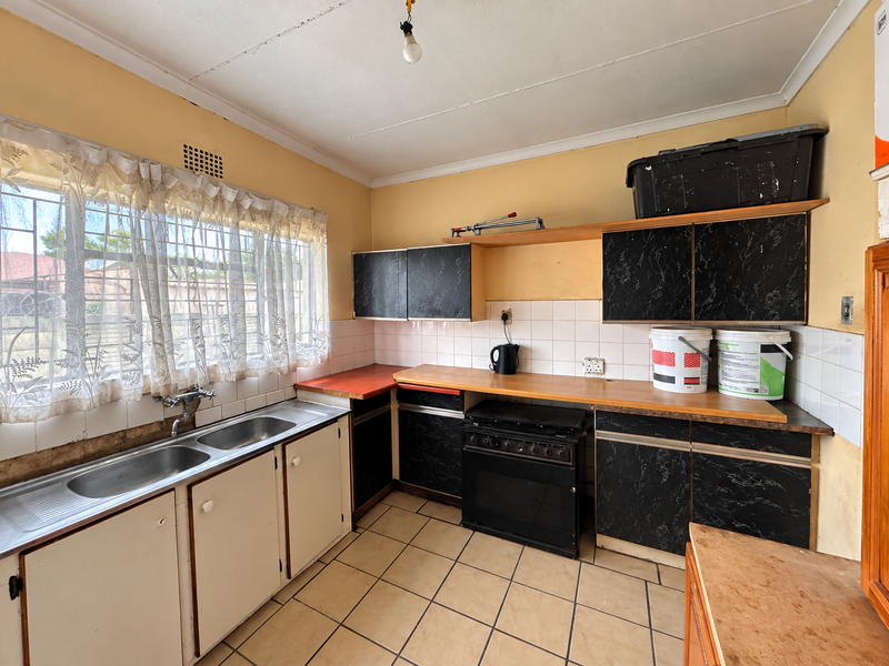 A functional kitchen featuring a double stainless steel sink, built-in oven, hob, and laminate countertops with ample storage cabinetry and tiled splashbacks.