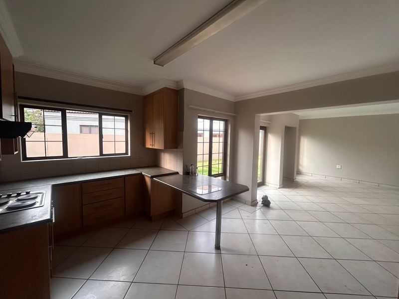 Open plan kitchen and living area featuring built-in wooden cabinetry, tiled flooring, and direct access to the exterior.