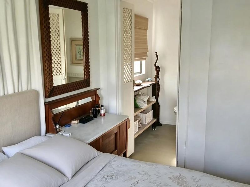 A cozy bedroom featuring a built-in vanity and a doorway leading to an adjoining space with louvered doors and a vaulted ceiling.