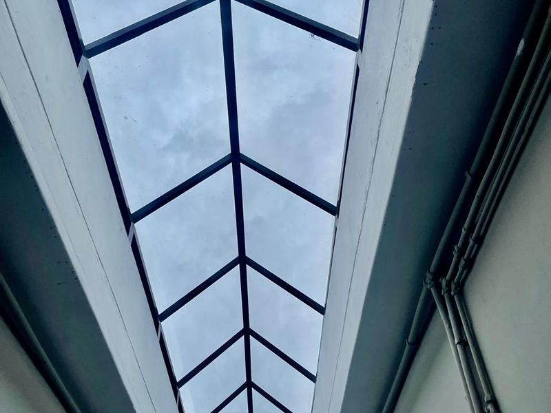 A bright hallway featuring a large, modern pitched skylight that provides ample natural light to the interior space.