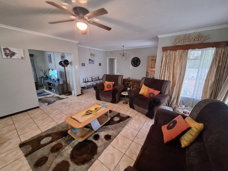 A spacious living room featuring tiled flooring, a ceiling fan, and coved ceilings, offering a comfortable and functional layout for relaxation.