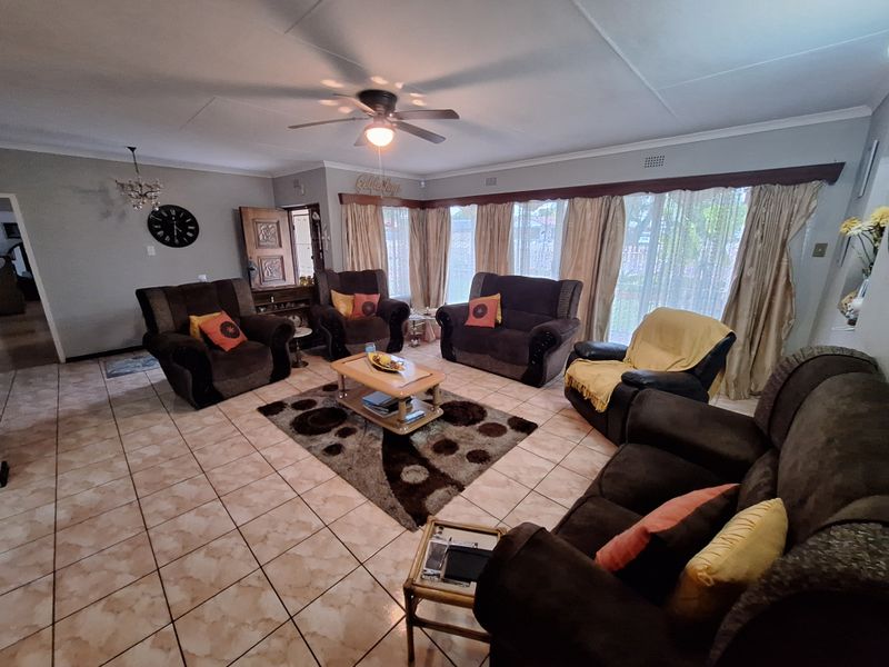 Spacious living room featuring tiled flooring, a ceiling fan, and large windows that provide ample natural light.