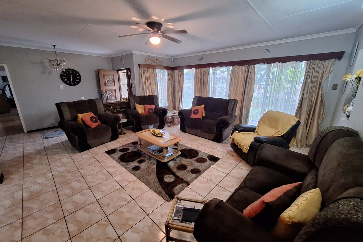 Spacious living room featuring tiled flooring, a ceiling fan, and large windows that provide ample natural light.