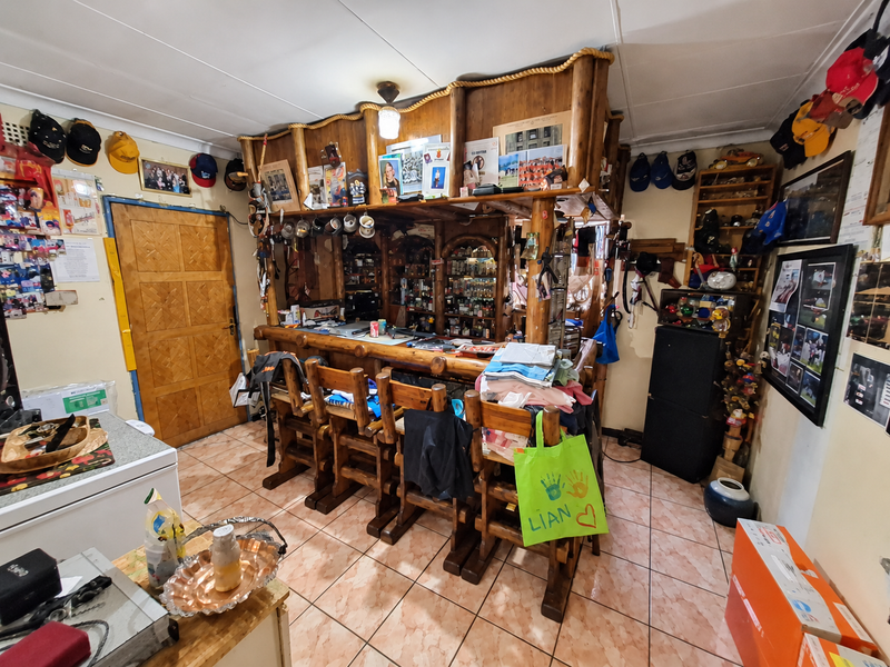 A rustic home bar area featuring a built-in wooden counter, tiled flooring, and a traditional wooden door, offering potential for a modern entertainment space update.
