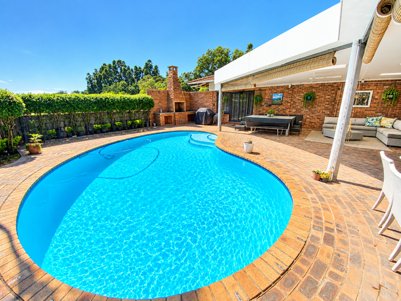 Outdoor entertainment area featuring a swimming pool, brick-paved patio, and a built-in brick braai, perfect for hosting and relaxation.