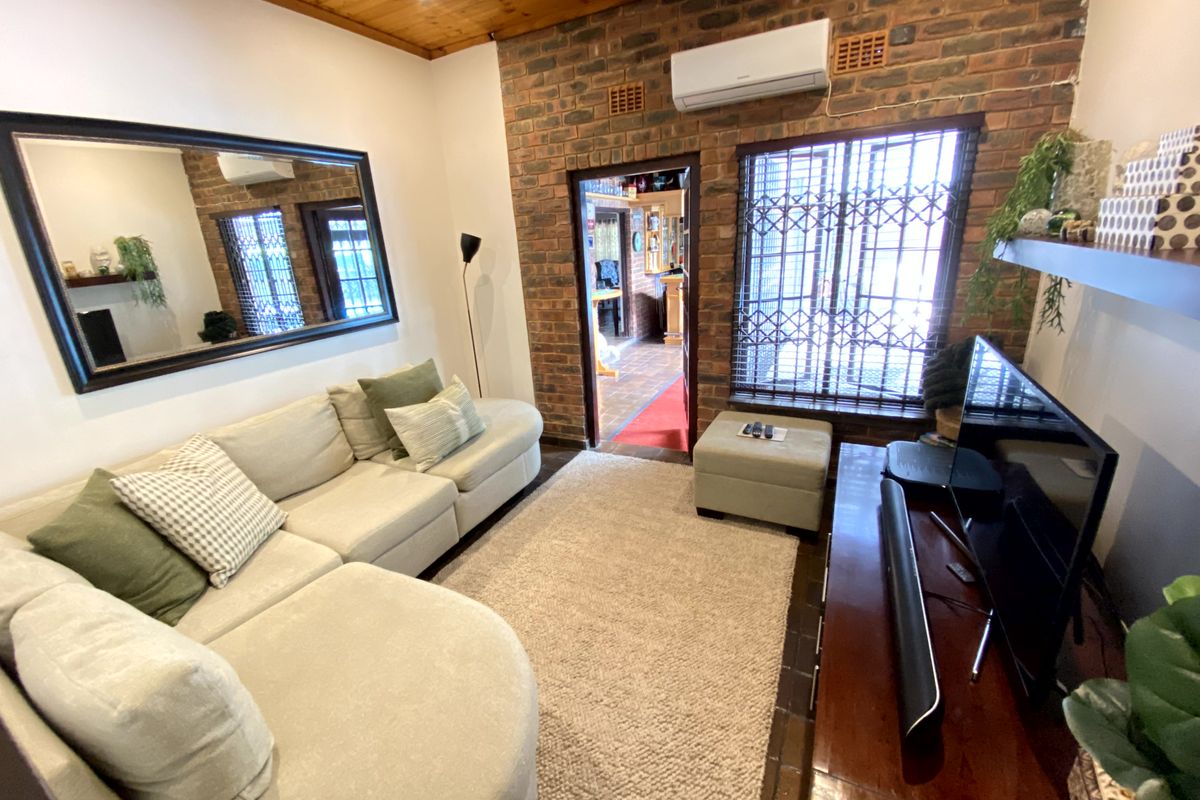Cozy living room featuring an exposed brick feature wall, timber ceiling, and split-system air conditioning, providing a warm and functional space.