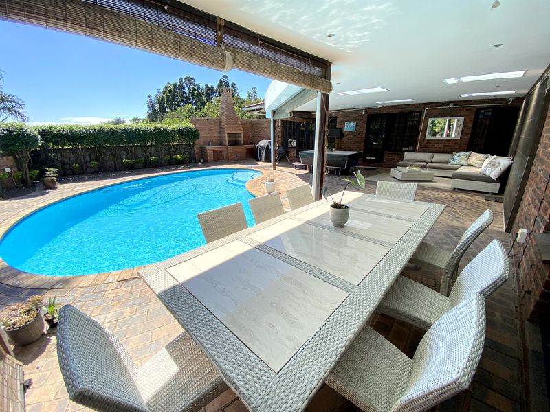 Spacious covered patio featuring a built-in brick braai, skylights, and direct access to a private swimming pool and paved outdoor area.