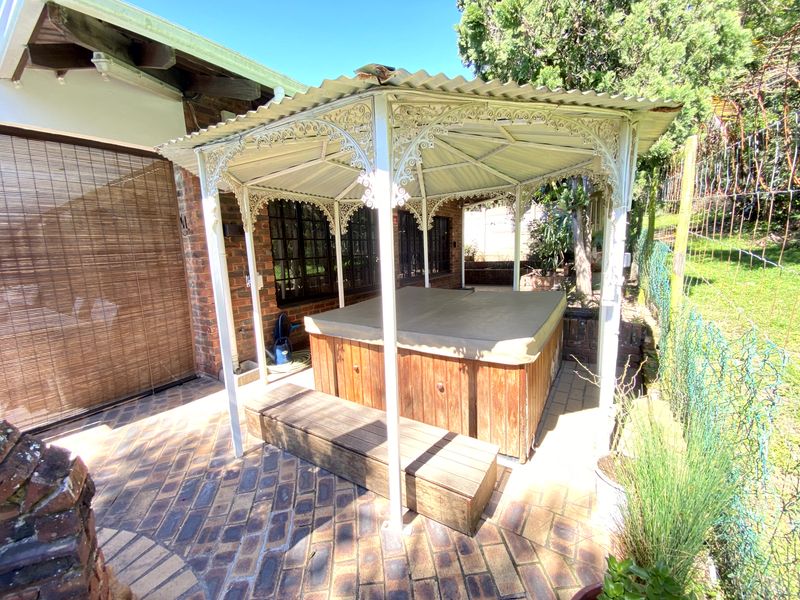 Outdoor entertainment area featuring a brick-paved patio with a covered wrought iron gazebo housing a built-in spa.