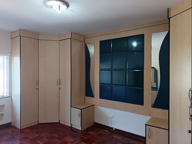 Bedroom featuring extensive built-in cabinetry with integrated mirrors and dark blue paneling, complemented by traditional parquet flooring.
