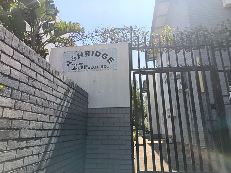 Front entrance view of Ashridge complex at 23 Povall Road, featuring a brick boundary wall and secure metal gate access.