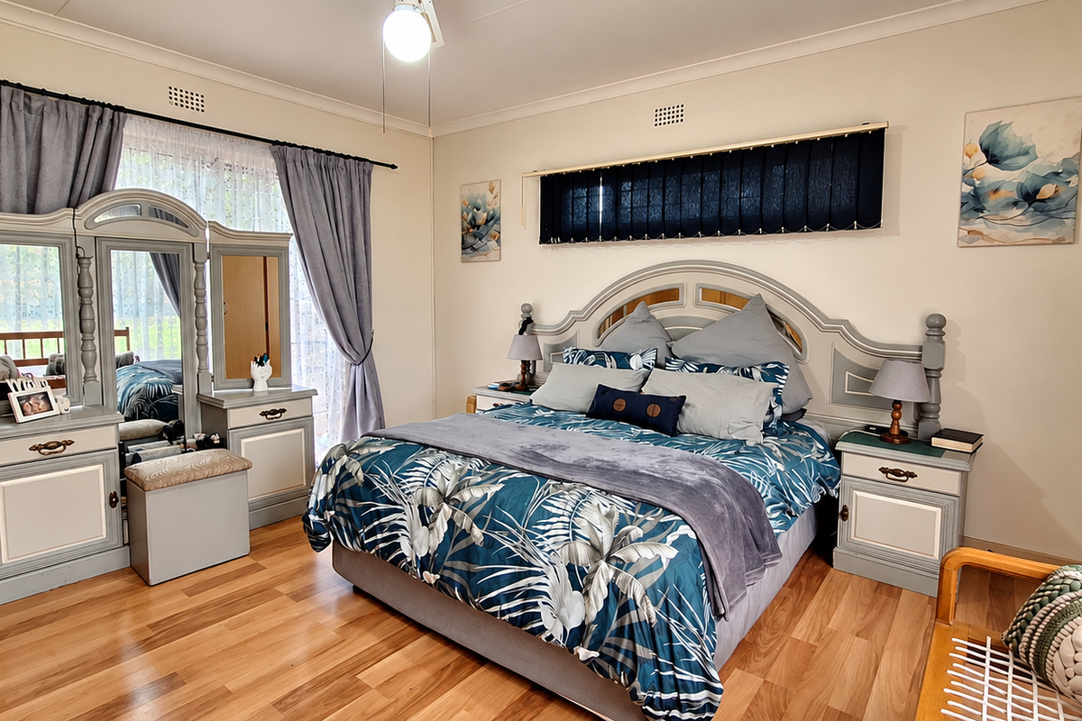 A well-maintained bedroom featuring laminate flooring, a ceiling fan, and built-in vanity and bedside cabinetry.