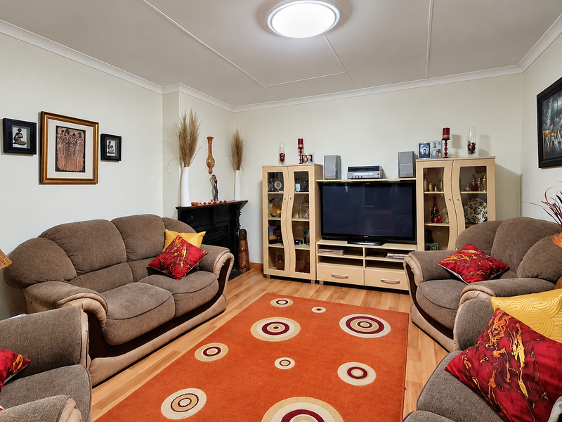 A comfortable living room featuring laminate flooring, a fireplace, and a central ceiling light fixture, providing a functional and inviting space.