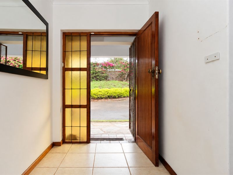 Entrance foyer featuring ceramic floor tiles, a solid timber front door with a leaded glass sidelight, and direct access to the exterior.