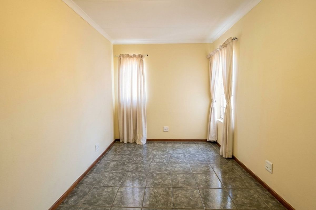 An empty bedroom featuring neutral walls, tiled flooring, and coved cornicing, providing a blank canvas for personalization.
