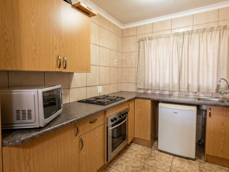 A functional kitchen featuring laminate cabinetry, built-in oven, electric hob, and tiled backsplash, offering a practical layout for daily meal preparation.