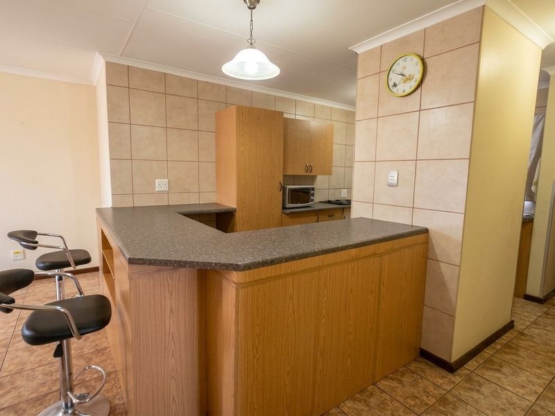 A functional kitchen featuring laminate cabinetry, a breakfast bar, tiled backsplash, and tiled flooring, providing a practical layout for daily use.
